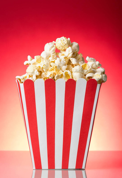 Salty popcorn in large square box on bright red. - Zdjęcie, obraz