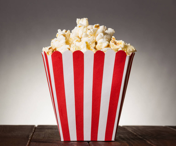 Large square box filled with top popcorn on gray background. - Valokuva, kuva