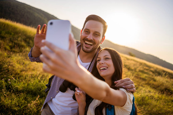 Happy couple is hiking in mountain. They are taking selfie. - Valokuva, kuva