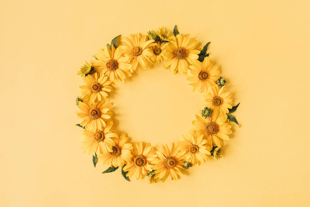Round frame border of yellow daisy flowers on yellow background. Mockup blank copy space. Flat lay, top view floral composition. - Foto, imagen