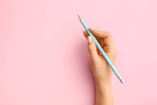 weibliche Hand mit Bleistift auf farbigem Hintergrund - Foto, Bild