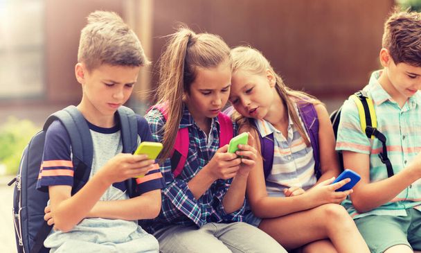elementary school students with smartphones - Foto, afbeelding