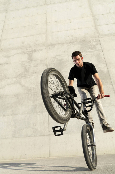 Young BMX bicycle rider on a grey urban concrete background - Foto, afbeelding