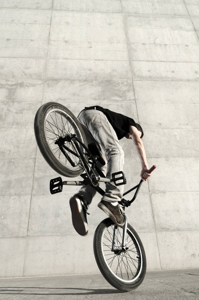 Young BMX bicycle rider on a grey urban concrete background - Photo, image