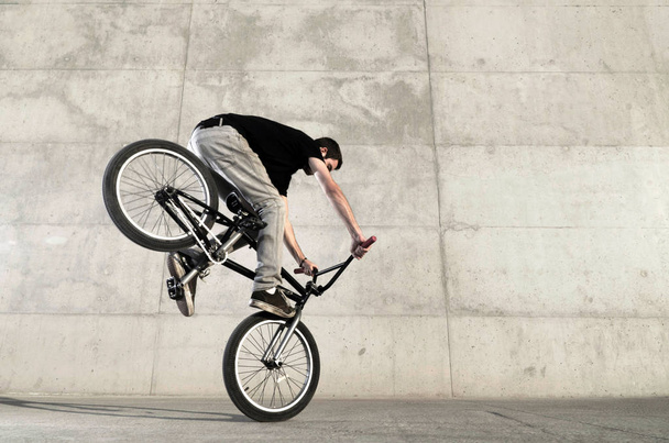 Young BMX bicycle rider on a grey urban concrete background - Фото, зображення