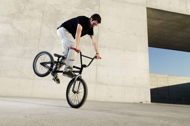 Young BMX bicycle rider on a grey urban concrete background - Fotó, kép