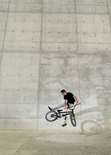 Young BMX bicycle rider on a grey urban concrete background - Fotoğraf, Görsel