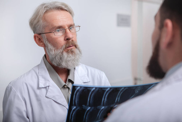 Senior male doctor talking to a colleague at the hospital - Photo, Image