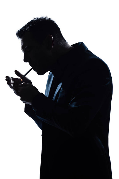 one caucasian man portrait smoking lighting cigarette silhouette in studio isolated white background - Foto, Imagem