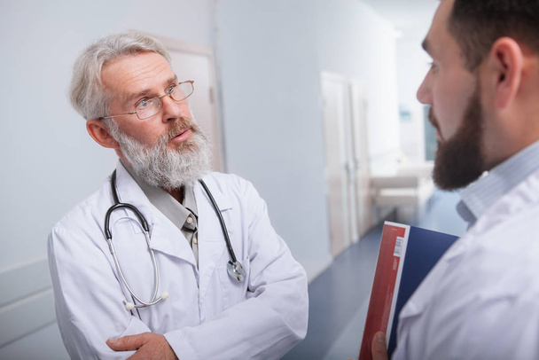 Medico anziano di sesso maschile che parla con un collega dell'ospedale
 - Foto, immagini
