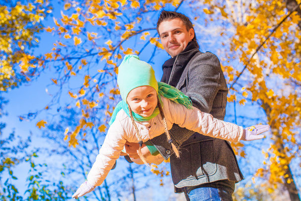 Little cute girl with happy father having fun in autumn park on a sunny day - Fotoğraf, Görsel