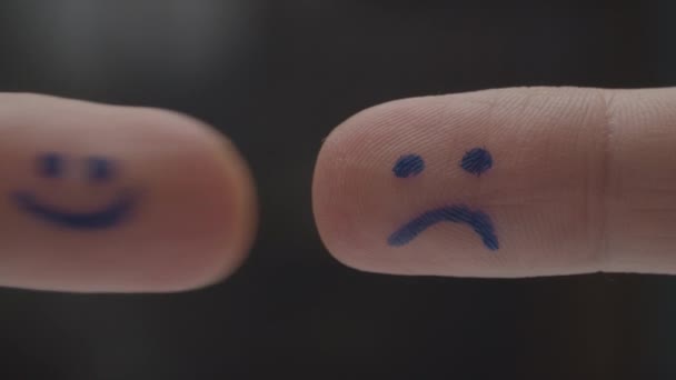 Two fingers with happy and sad smileys on finger pads meeting each other and interacting. Happy sad emotions in signs. Macro view.  - Filmagem, Vídeo