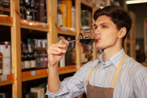 Young male sommelier working at wine store - Фото, зображення