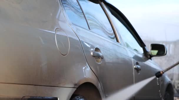 autowaschanlage: ein mann wäscht ein auto unter wasserdruck und reibt das glas. Pflegekonzept für Autos - Filmmaterial, Video