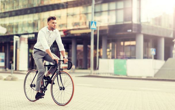 man with headphones riding bicycle on city street - Фото, изображение