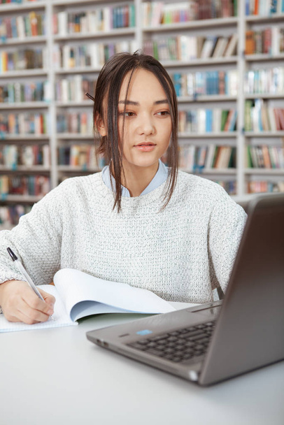 Houkutteleva aasialainen nainen opiskelee kirjastossa
 - Valokuva, kuva
