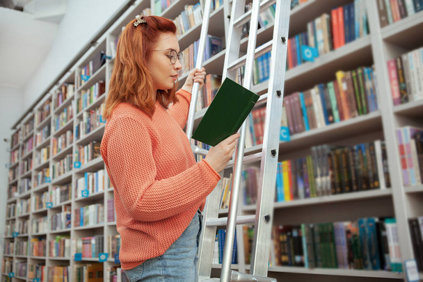 Mujer joven leyendo en la biblioteca
 - Foto, imagen