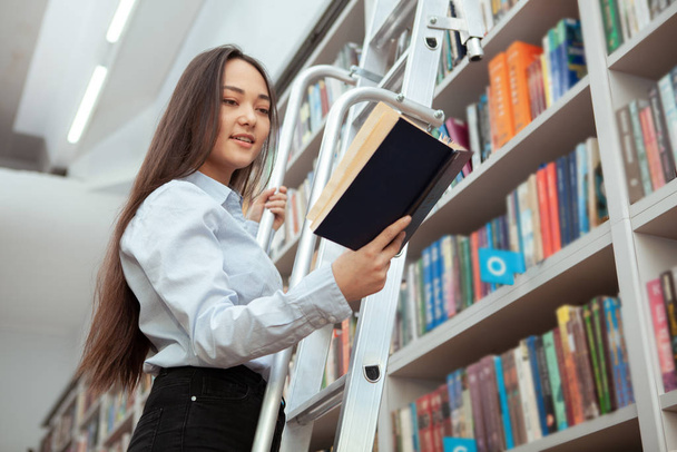 attraente asiatico donna lettura a il biblioteca
 - Foto, immagini