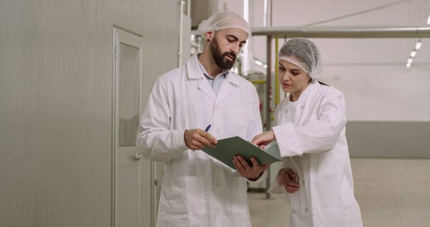 Κατασκευή αρτοποιίας φούρναρης και μηχανικός περπατήματος μέσα από το εργοστάσιο συνομιλεί συγκεντρωμένο μηχανικό άνθρωπος κρατώντας ένα χάρτη - Φωτογραφία, εικόνα