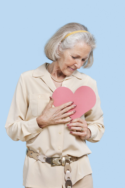ανώτερος γυναίκα που κρατά την καρδιά κόκκινο χαρτί - Φωτογραφία, εικόνα