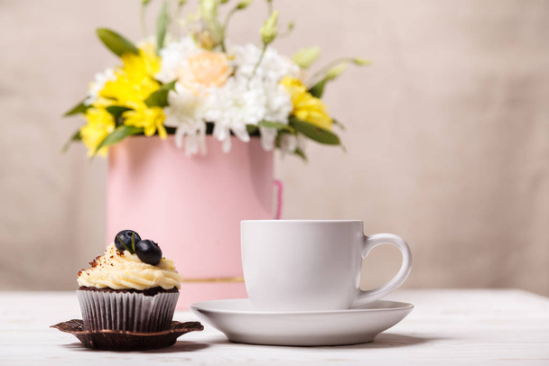 Cup of coffee and a cupcake with whipped cream, a bouquet of spring flowers. Romantic love background. - Fotó, kép