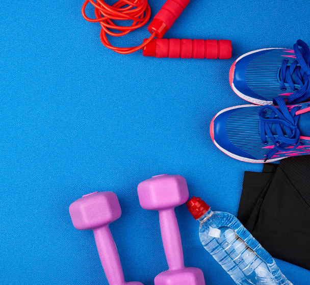mancuernas de plástico púrpura, ropa deportiva, agua, zapatillas de deporte de color rosa en un
  - Foto, imagen