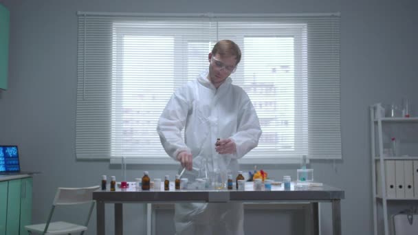 Hombre en ropa de trabajo protectora tomar sustancia del tubo en el laboratorio
 - Imágenes, Vídeo