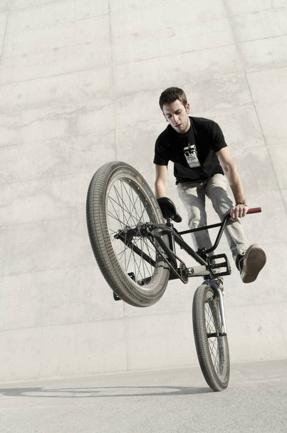 Young BMX bicycle rider on a grey urban concrete background - Fotó, kép