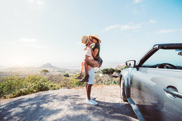 Romantic escape in Tenerife . Couple in love kissing on a cliff at road trip with a convertible car - Foto, Imagen