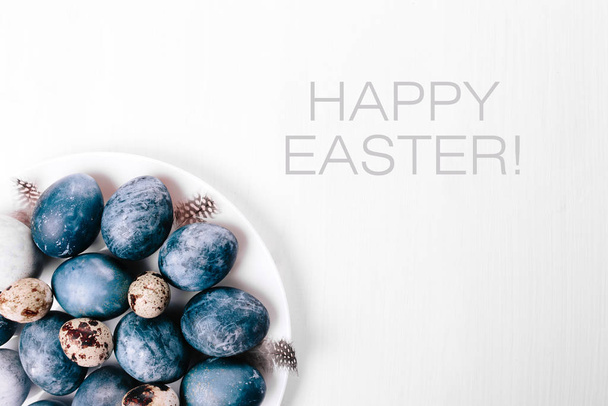Beautiful group ombre blue Easter eggs with quail eggs and feathers on a white wooden background. Easter concept. Border eggs. Copy space for text. - Fotografie, Obrázek