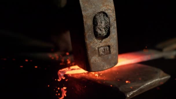 SLOW MOTION, MACRO, DOF: Bright orange steel blade getting forged by unrecognizable craftsman. Tiny particles flying away from glowing hot blade after getting struck by a heavy blacksmith's hammer - Footage, Video