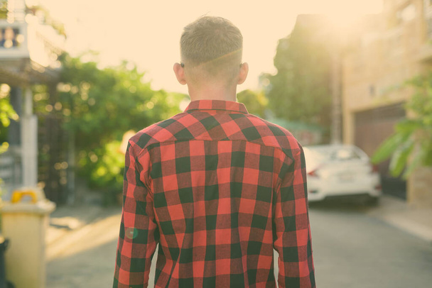 Young man wearing red checkered shirt in the streets outdoors - Foto, imagen