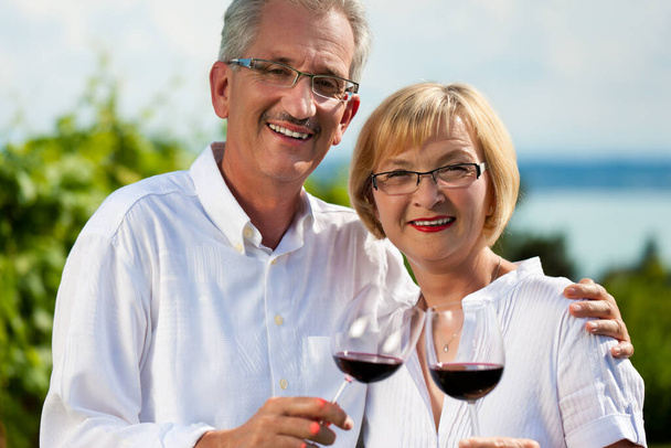 happy couple drinking wine at lake in summer - Фото, зображення