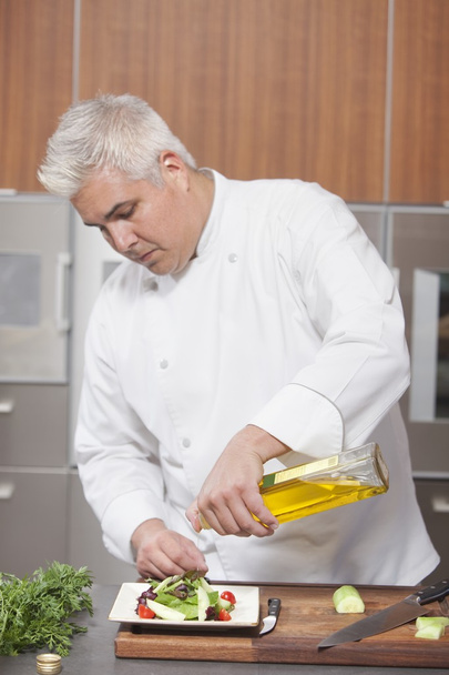 Chef pouring olive oil over salad - Foto, Imagem