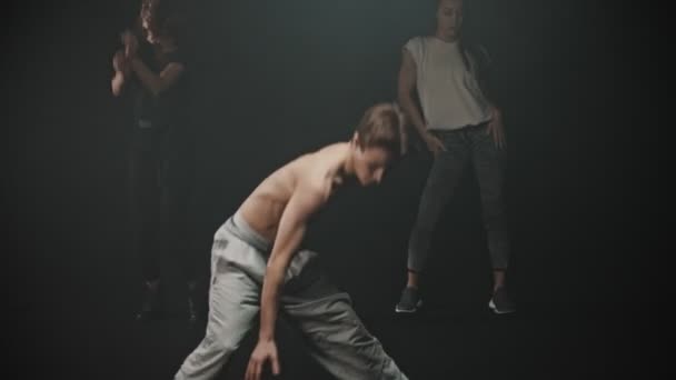 Um homem sem camisa realizando truques de breakdancing - duas mulheres dançando no fundo
 - Filmagem, Vídeo