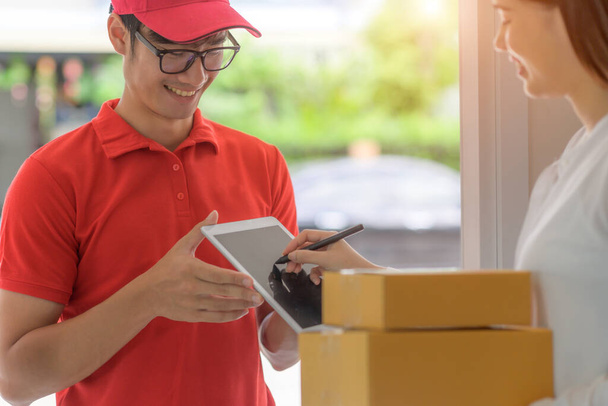 delivery boy in charge of sending packages parcel to customer, device signed received report online to completed parcel delivered - Fotografie, Obrázek