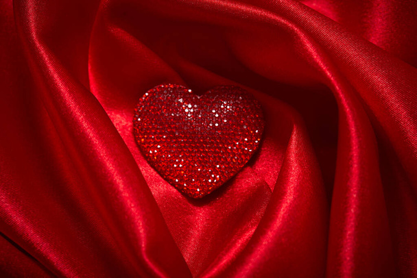 schönes rotes Schmuckherz zum Valentinstag auf schönem Seidenstoff, Nahaufnahme - Foto, Bild