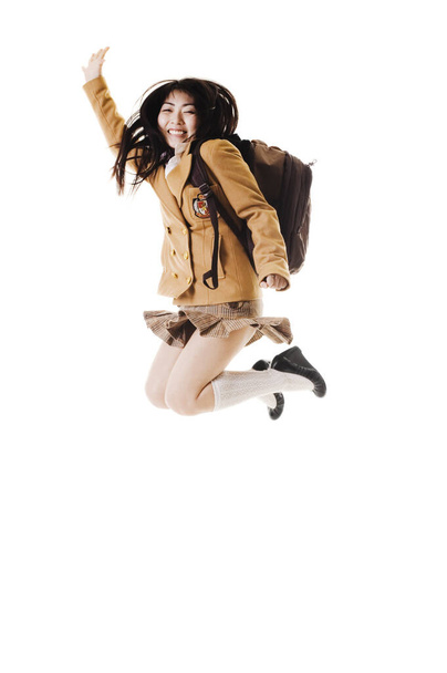 Female Chinese student wearing a backpack on a white background jumping into the air. - Фото, зображення