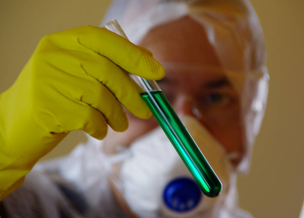 Ученый в защитной одежде с жидкостью в пробирке в хань
 - Фото, изображение