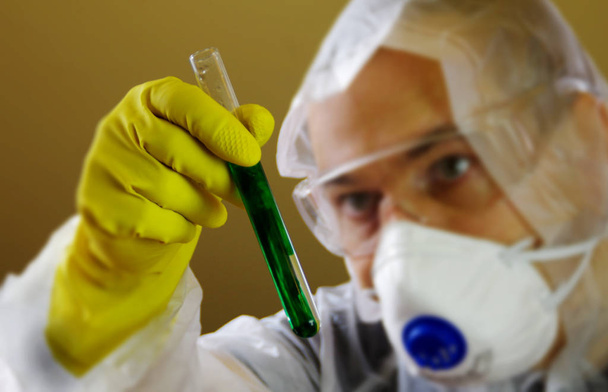 Ученый в защитной одежде с жидкостью в пробирке в хань
 - Фото, изображение