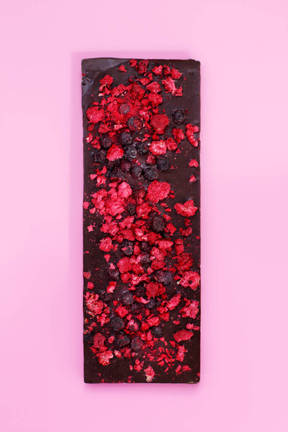 Dark chocolate with dried red berries on bright pink background - Foto, immagini