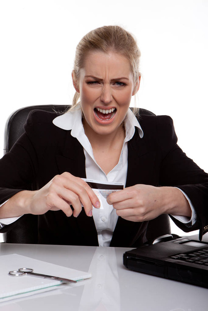 Businesswoman Throwing A Tantrum holding her credit card in her hands, seated at desk. - Фото, зображення
