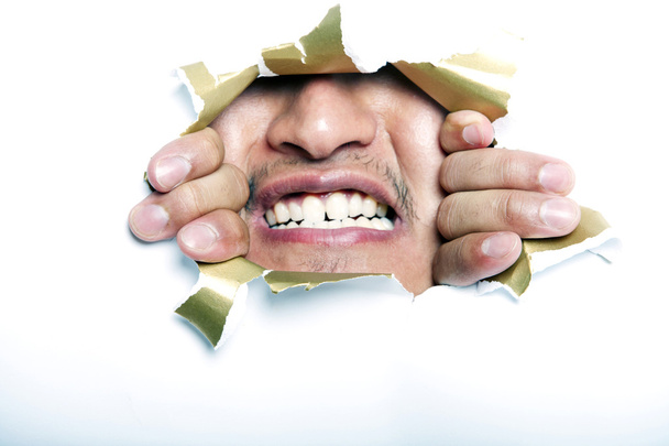 Man looking through ripped paper hole - Foto, Imagen