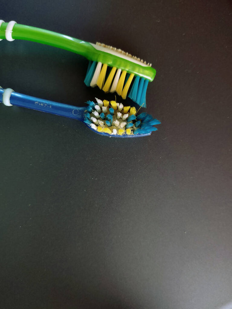 Imagem de par de escova de dentes verde e azul sob céu aberto com árvore no fundo
 - Foto, Imagem