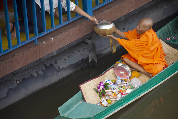Таїландці моляться, кладучи їжу та приношення монахам. - Фото, зображення