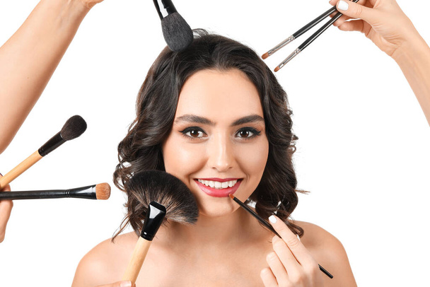 Makeup artists working with beautiful young woman on white background - Zdjęcie, obraz