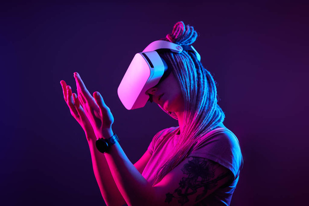 La mujer está usando auriculares de realidad virtual. Retrato de estudio de luz de neón. - Foto, Imagen