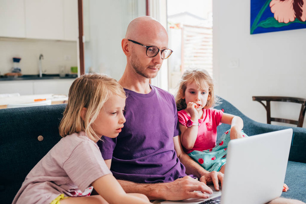 Vader kijken streaming cartoon op de computer met twee dochters - Foto, afbeelding