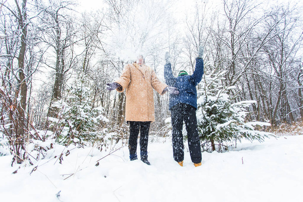 Концепція батьківства, веселощів і сезону Щаслива мати і син розважаються і граються зі снігом в зимовому лісі
 - Фото, зображення