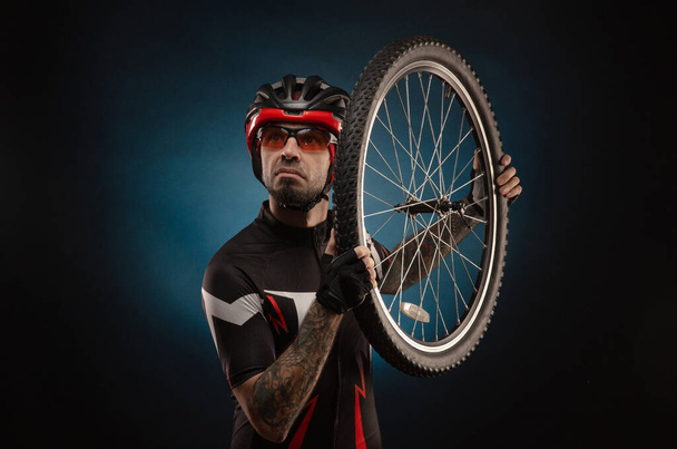 парень-велосипедист в велосипедном шлеме с велосипедным колесом
 - Фото, изображение